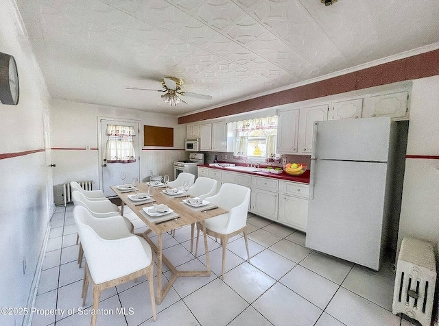 kitchen with a healthy amount of sunlight, light tile patterned floors, white appliances, and white cabinets