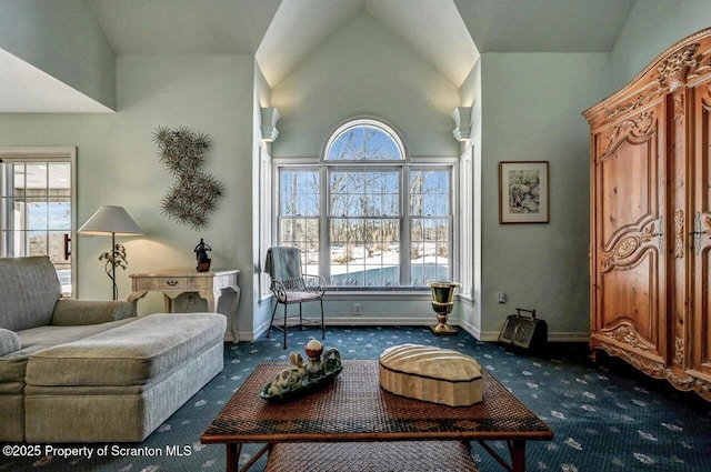 living area featuring high vaulted ceiling, dark colored carpet, and baseboards