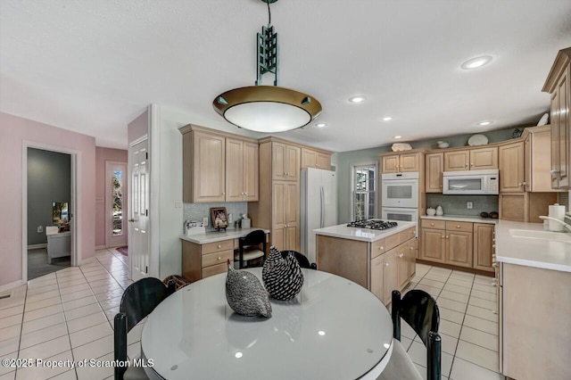 kitchen featuring light tile patterned flooring, white appliances, light countertops, and light brown cabinetry