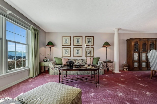 living area with a textured ceiling, carpet flooring, decorative columns, and baseboards