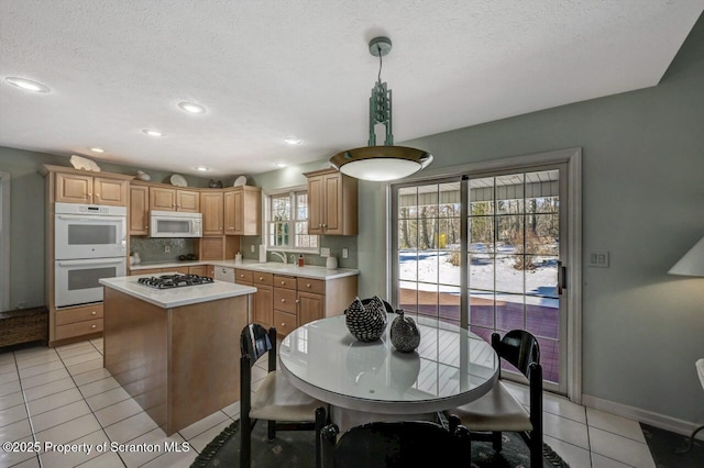 kitchen with white appliances, tasteful backsplash, light tile patterned floors, a center island, and light countertops