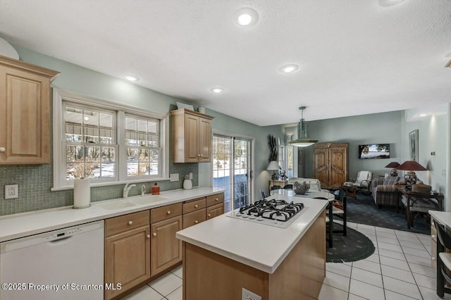 kitchen featuring light countertops, white appliances, a kitchen island, and a sink