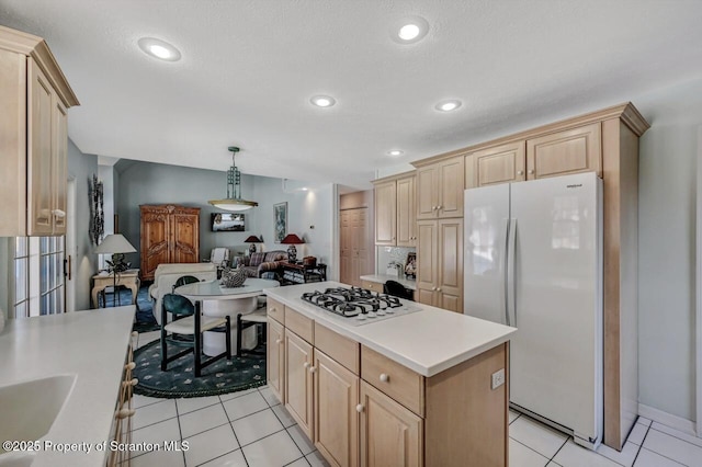 kitchen featuring gas cooktop, open floor plan, light countertops, hanging light fixtures, and freestanding refrigerator