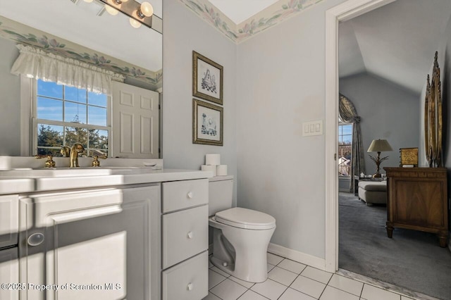 bathroom with tile patterned flooring, a healthy amount of sunlight, vaulted ceiling, and vanity