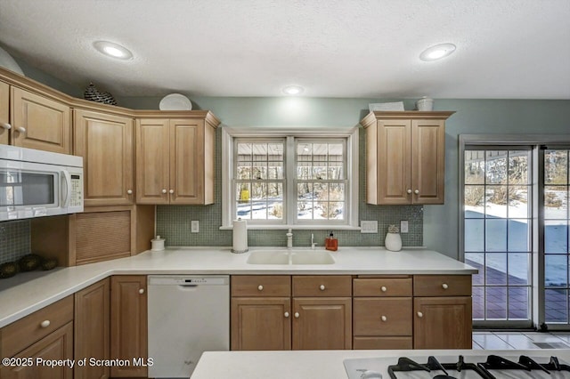 kitchen featuring white appliances, decorative backsplash, light countertops, a sink, and recessed lighting