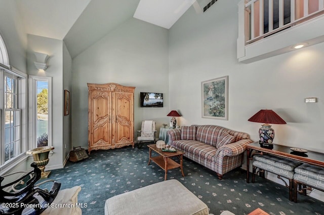 living area with dark colored carpet, high vaulted ceiling, visible vents, and baseboards