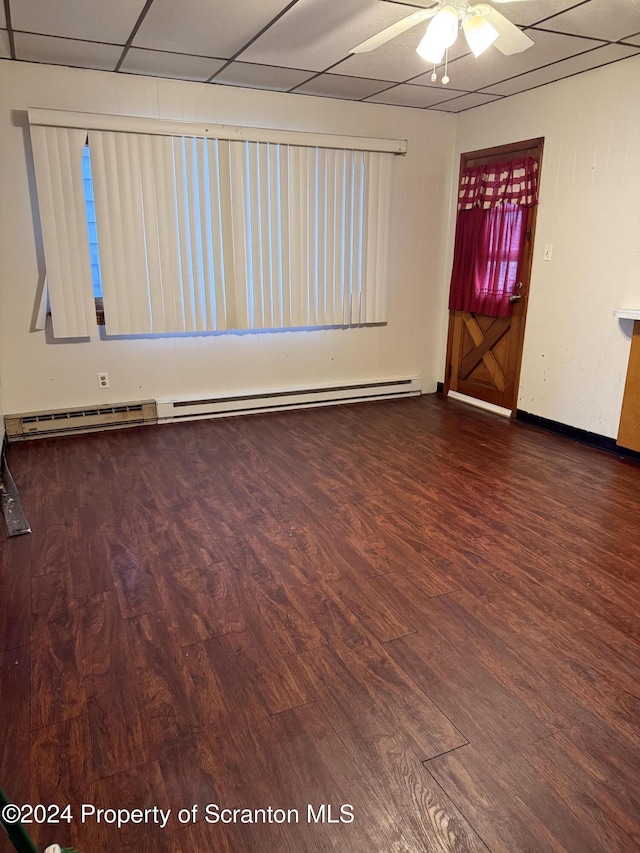 unfurnished room with baseboard heating, ceiling fan, a drop ceiling, and wood-type flooring