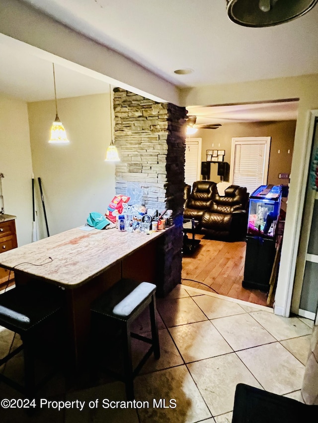 kitchen with decorative light fixtures, ceiling fan, a kitchen bar, and light tile patterned floors