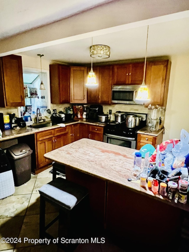 kitchen featuring sink, stove, pendant lighting, a breakfast bar, and light tile patterned floors