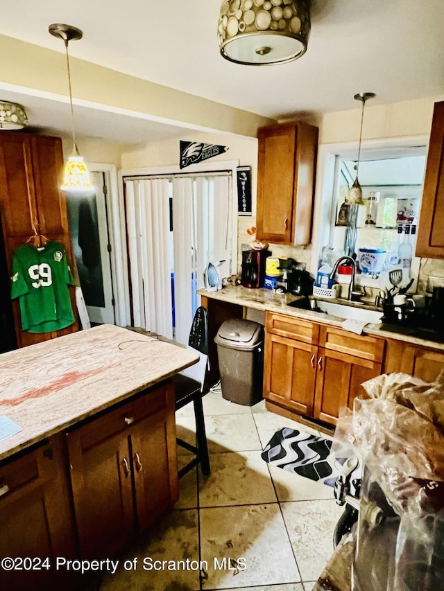 kitchen with pendant lighting, light tile patterned floors, a breakfast bar area, and sink