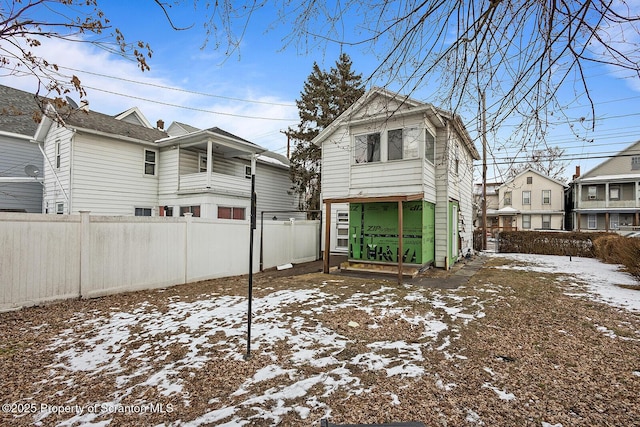 snow covered house with a residential view and a fenced backyard