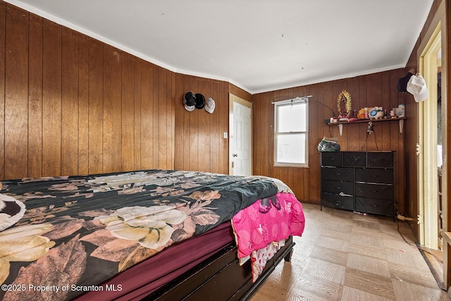 bedroom featuring crown molding and wooden walls