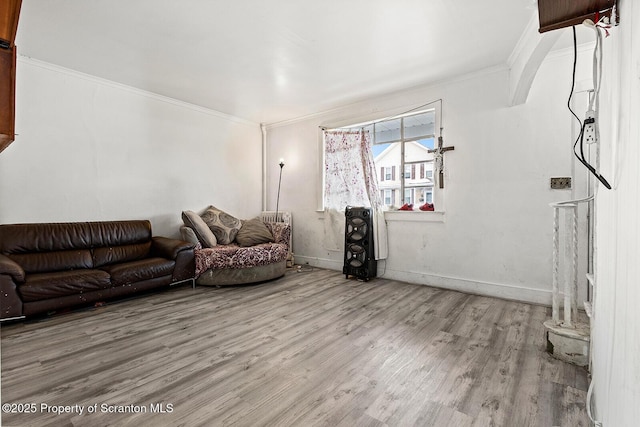 living room featuring baseboards, ornamental molding, and wood finished floors