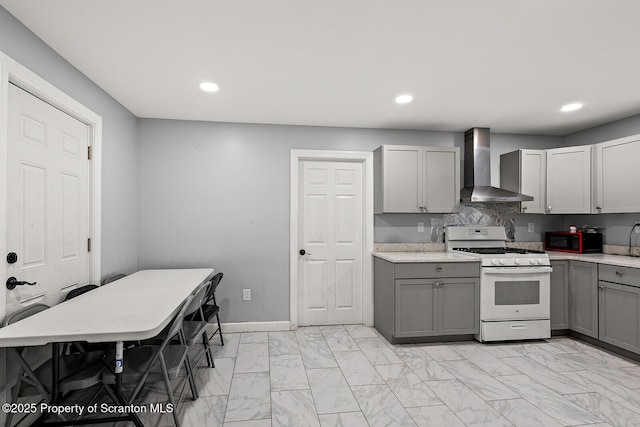 kitchen featuring gray cabinets, wall chimney range hood, and white gas stove