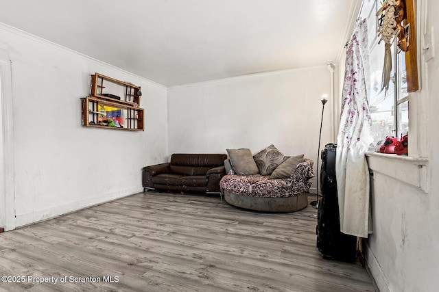 living area with wood finished floors, crown molding, and baseboards