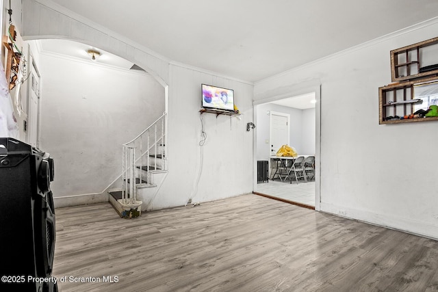 interior space featuring arched walkways, wood finished floors, crown molding, and stairway