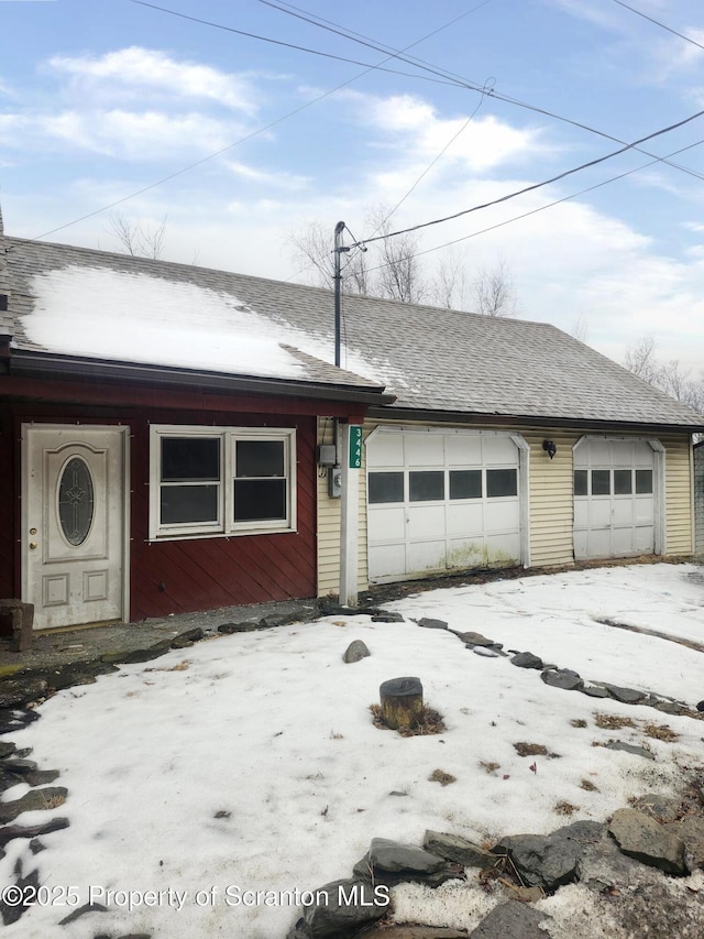 view of front of property featuring a garage and roof with shingles