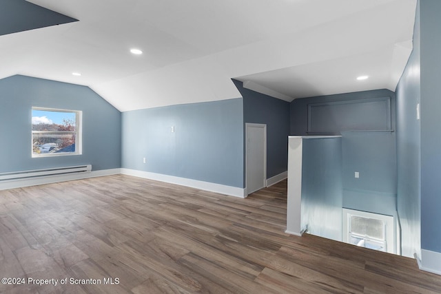 additional living space featuring baseboard heating, vaulted ceiling, and hardwood / wood-style flooring