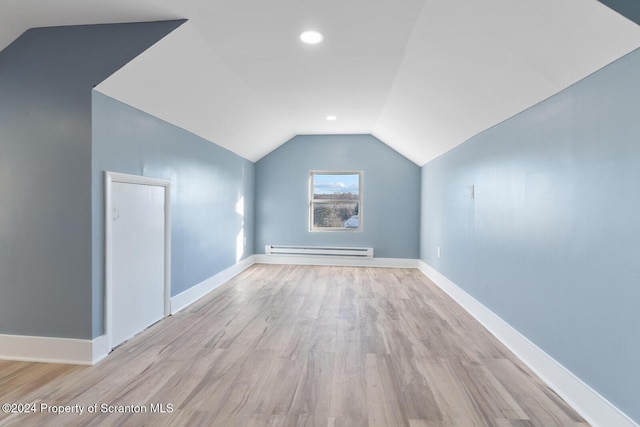 bonus room with baseboard heating, light hardwood / wood-style flooring, and lofted ceiling