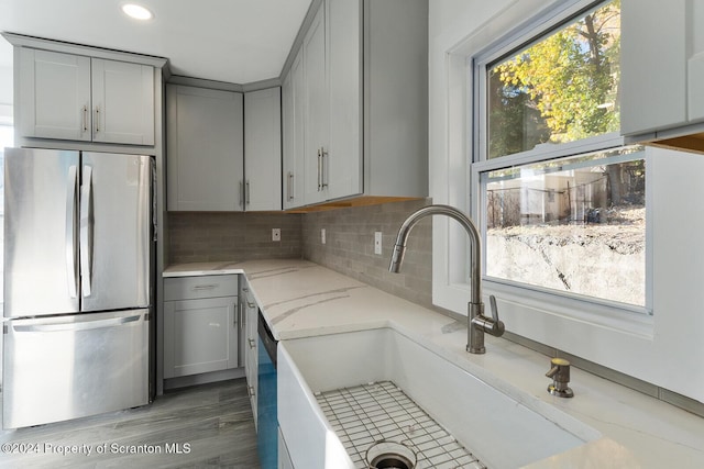 kitchen featuring gray cabinetry, decorative backsplash, sink, and stainless steel refrigerator