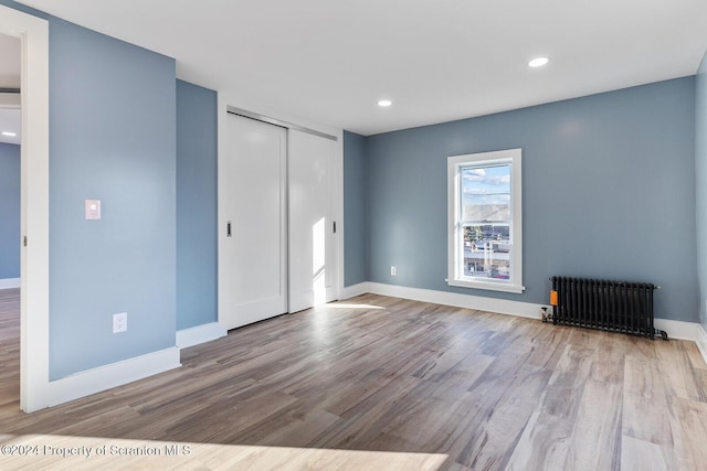 spare room with radiator heating unit and light hardwood / wood-style flooring