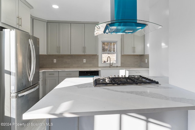 kitchen with island exhaust hood, light stone countertops, gray cabinetry, stainless steel appliances, and sink