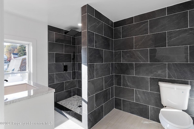 bathroom with vanity, tile patterned floors, toilet, tile walls, and a tile shower