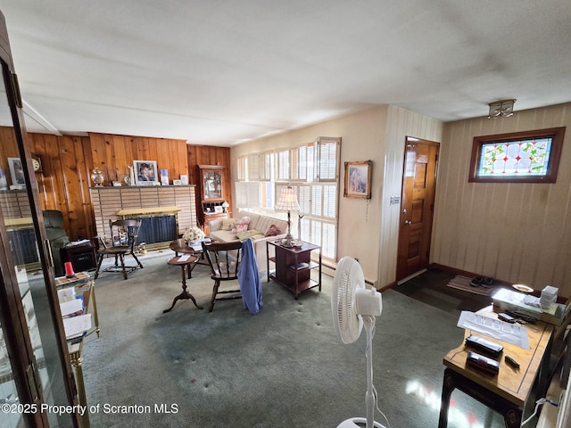 living room featuring a brick fireplace, wooden walls, and dark carpet