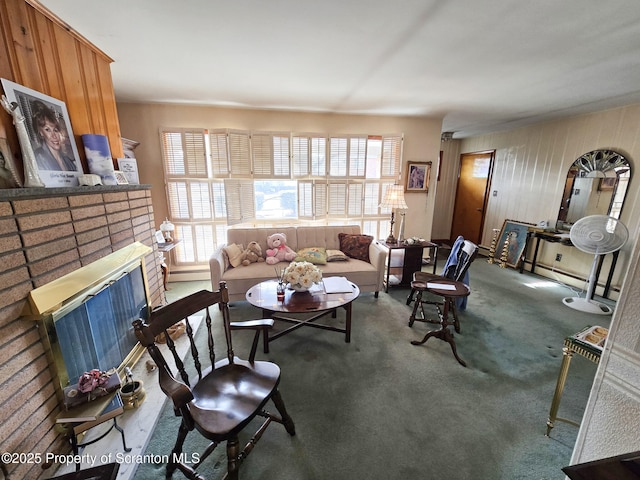 carpeted living room with a brick fireplace and wooden walls