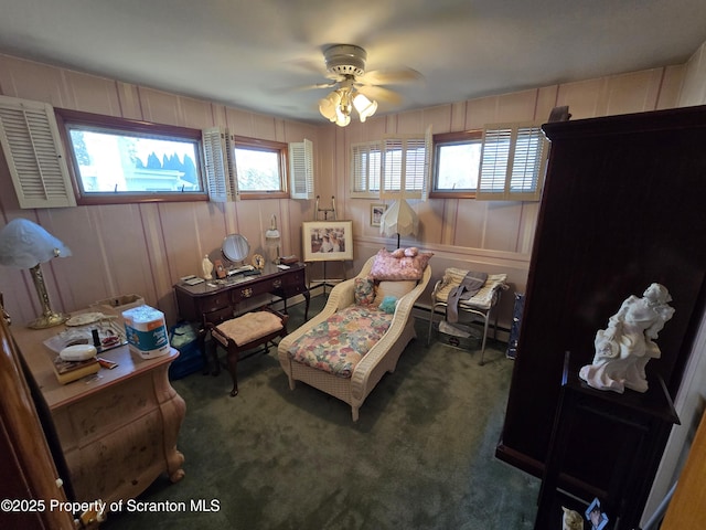 living area featuring dark carpet and ceiling fan