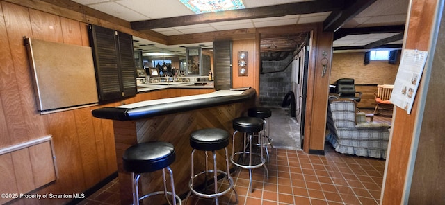 bar with dark tile patterned floors and a paneled ceiling