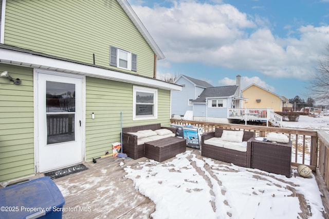 snow covered back of property featuring a wooden deck and outdoor lounge area