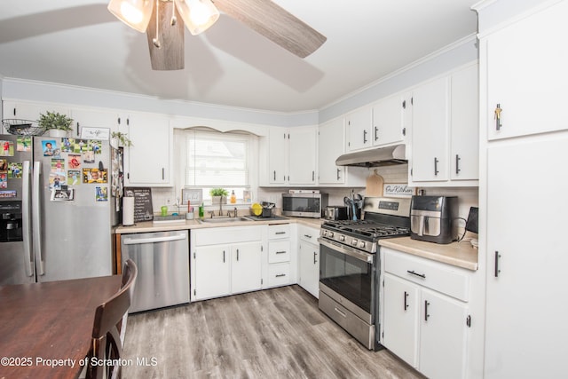 kitchen featuring appliances with stainless steel finishes, white cabinetry, sink, backsplash, and ceiling fan