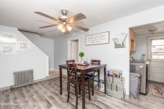 dining area with washing machine and clothes dryer, radiator heating unit, ornamental molding, ceiling fan, and light hardwood / wood-style floors