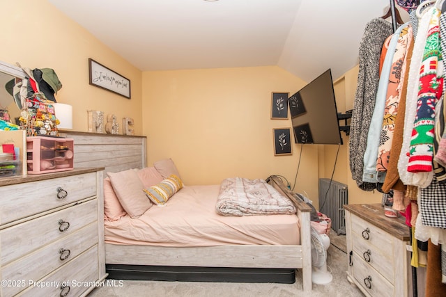 bedroom featuring vaulted ceiling, radiator, and light carpet