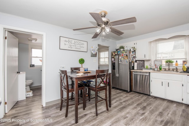 dining area with crown molding, sink, and light hardwood / wood-style flooring