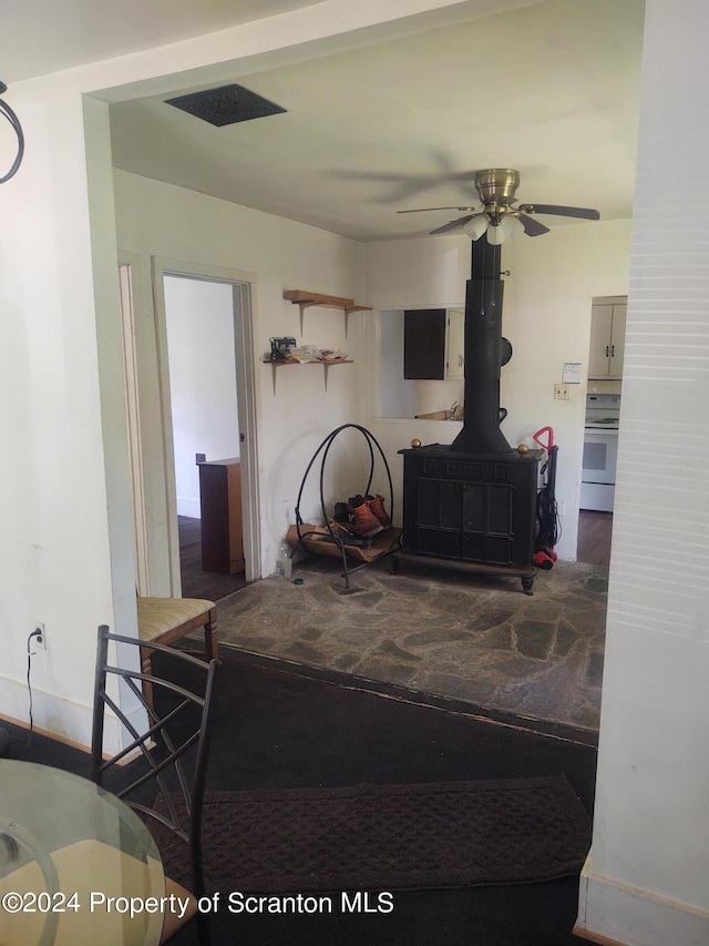 living room with ceiling fan and a wood stove