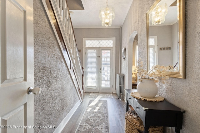 entrance foyer with wood finished floors, a chandelier, stairs, and ornamental molding