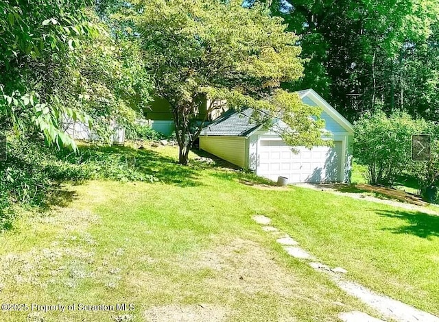 view of yard with a garage and an outbuilding