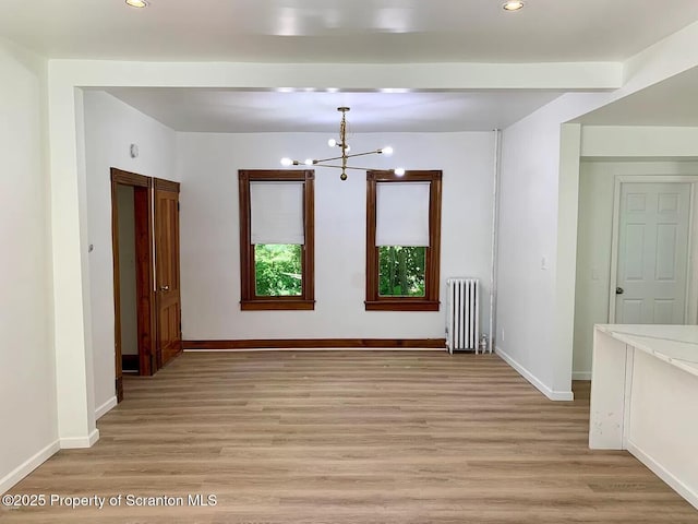 unfurnished room with radiator, a chandelier, and light wood-type flooring