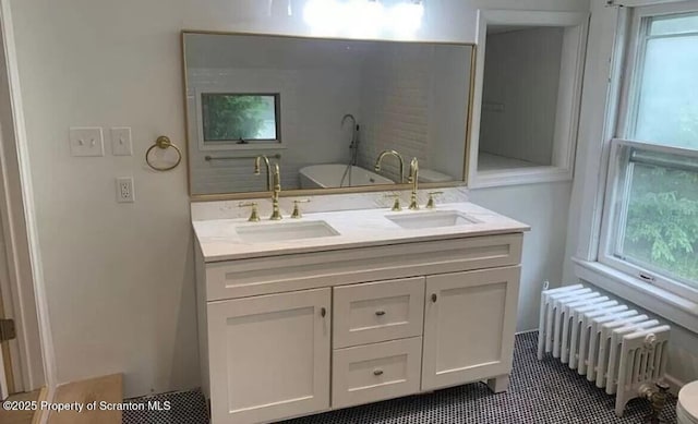 bathroom featuring a bathtub, radiator heating unit, vanity, and a healthy amount of sunlight