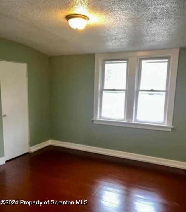 unfurnished room with dark wood-type flooring and a textured ceiling