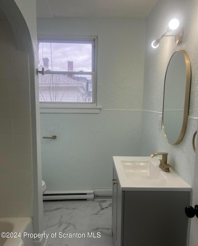 bathroom featuring vanity, toilet, baseboard heating, and a washtub