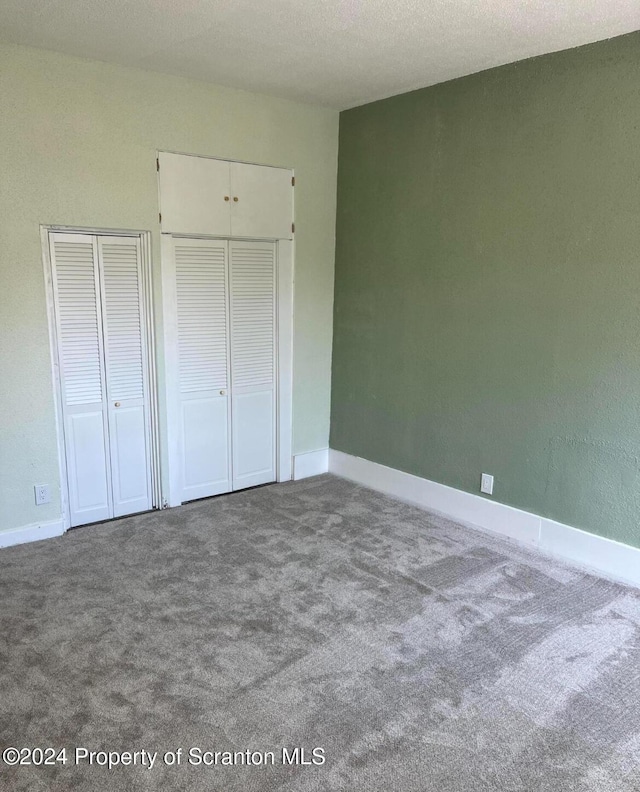 unfurnished bedroom with carpet floors and two closets