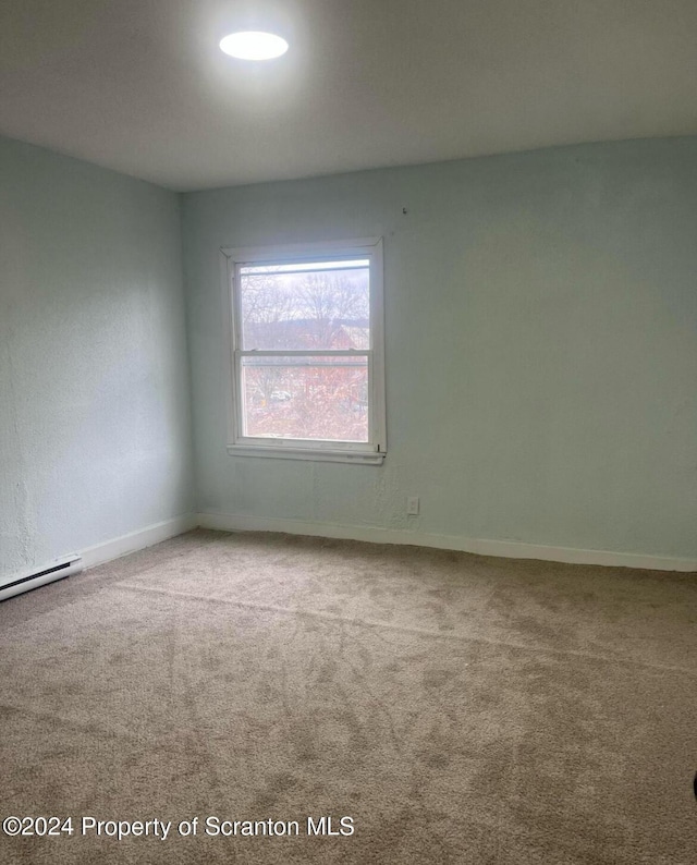 carpeted spare room featuring baseboard heating