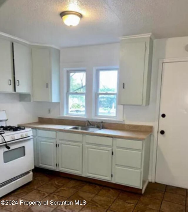 kitchen featuring white cabinets, a textured ceiling, white gas range, and sink