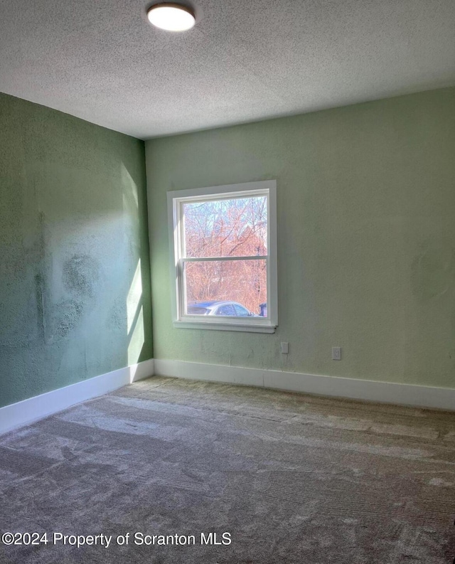 carpeted empty room featuring a textured ceiling