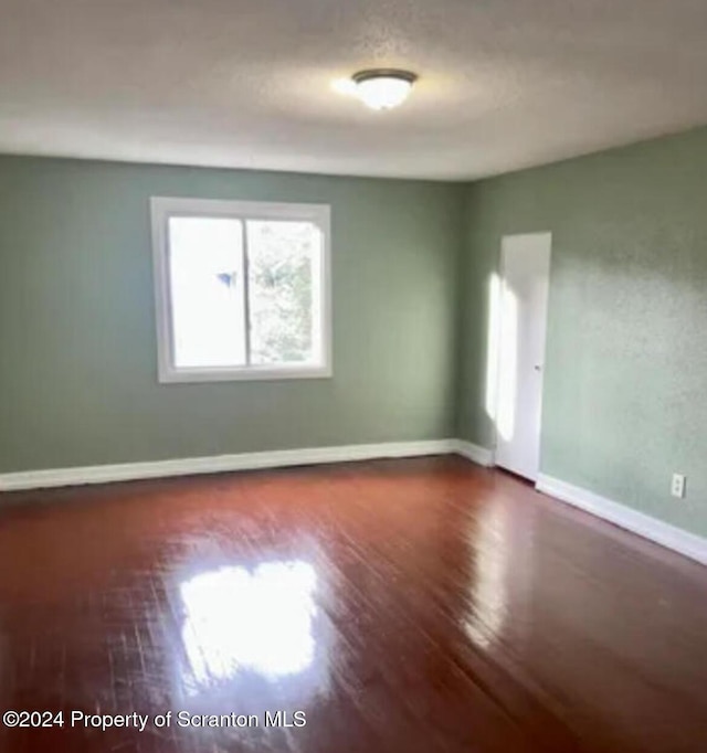 unfurnished room with dark wood-type flooring