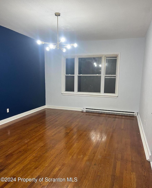 spare room featuring a baseboard radiator, dark hardwood / wood-style floors, and a notable chandelier