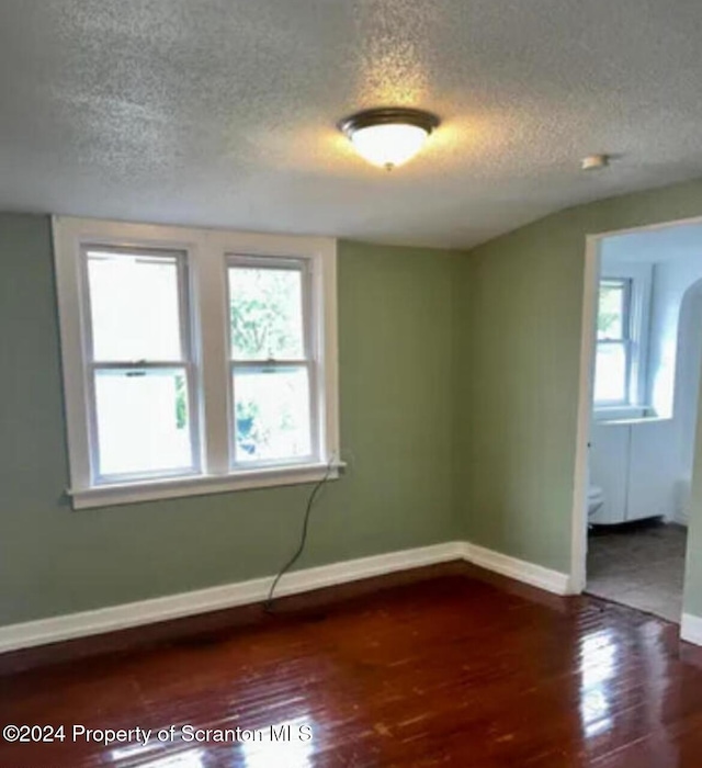 empty room with wood-type flooring and a textured ceiling